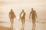 Older surfers carrying board on beach