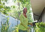 Older woman watering plants in backyard