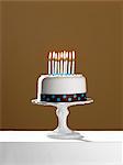 Birthday cake with lit candles on cake stand