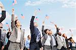 Smiling business people in crowd waving American flags