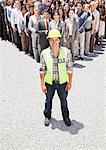 Portrait of smiling construction worker with business people in background