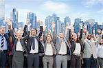 Business people cheering with arms raised in front of skyline