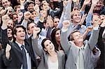 Smiling crowd of business people cheering with arms raised