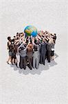 Crowd of business people in huddle lifting globe overhead