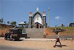 Man carrying firewood on his head walking past a church in rural Kerala, India, Asia