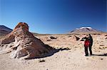 Couple looking at volcano on Altiplano, Potosi Department, Bolivia, South America