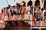 Young men celebrating Holi festival by splashing colored fluids on temple visitors, Nandgaon, Uttar Pradesh, India, Asia