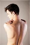 Close-up, Backview of Young Man Rubbing Shoulders with Hands, Studio Shot