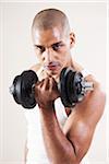 Portrait of Man Looking at Camera, Lifting Barbell Weights doing Bicep Curls, Studio Shot