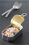 Variety of Pills in Opened Tin with Forks in Background, Studio Shot