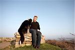 One man and his dog sitting on a wall