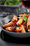 Italian food. Pasta penne with tomato sauce, olives and garnish