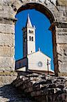 White Church Framed in the Arch of Ancient Roman Amphitheater in Pula, Istria, Croatia