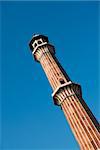 High minaret in Jama Masjid Mosque, Dehli, India with blue sky on background