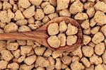 Soybean protein chunks in an olive wood spoon and forming a background.