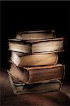 Dark and moody still life with worn and tattered old books.