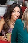 Astonished mature woman talking with friend in coffeehouse