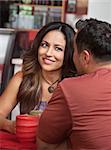 Skeptical Hispanic woman listening to man talk in cafe