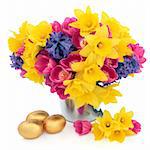 Tulip, daffodil and hyacinth flower arrangement in a metal vase with chocolate golden easter egg group over white background.