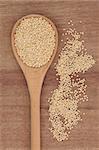 Quinoa grain in wooden spoon over papyrus background.