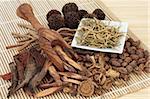 Chinese herbal medicine selection in a porcelain dish, scoop and loose over bamboo mat.