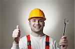 Happy young handyman with yellow hard hat and wrench