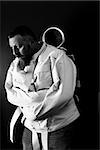 Photo of a insane man in his forties wearing a straitjacket leaning up against an asylum door.