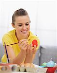 Happy young woman drawing on Easter red egg