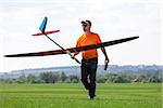 Man holds the RC glider, on grass field