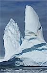 A large iceberg with two peaks floating in the ocean.