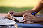 Young women and education, close up of hands of girl studying for college exam in park. Side view, copy space