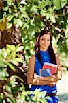 Sequence of students portrait at school, happy young woman smiling with college textbooks in park leaning on tree