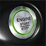 close up of a metallic engine start and stop button, green light, blur effect, automotive starter concept. Black background