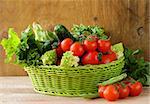 fresh vegetables (cucumbers, tomatoes, cabbage romanesco and green beans ) and herbs mix in a wicker basket