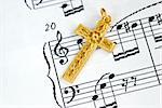 A golden cross on the top of a music sheet concept of religion