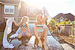 A family washes their car in the driveway of their home on a sunny summer afternoon in Portland, Oregon, USA