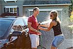 Couple washing their car in the driveway of their home on a sunny summer afternoon in Portland, Oregon, USA