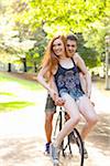 Young couple riding bike together in a park on a warm summer day in Portland, Oregon, USA