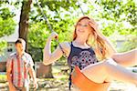 Young couple spend time on the swingset in park on a warm summer day in Portland, Oregon, USA