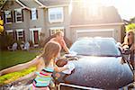 Family washing their car in the driveway of their home on a sunny summer afternoon in Portland, Oregon, USA