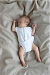 newborn baby girl in a white undershirt sleeping on a bed, Ontario, Canada