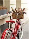 red, classic, road bicycle with wicker basket attached to handlebars filled with baguettes from bakery, Paris, France