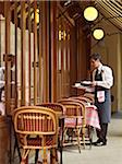 waiter clearing dishes at charming outdoor cafe, Fontaine de Mars, Paris, France