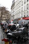 Selective focus on motorcycles parked in row along street on overcast winter day, Paris, France