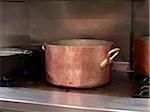 large copper pot on commercial stainless steel stove in restaurant kitchen