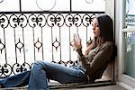 Woman using cell phone in windowsill