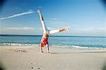 Woman doing cartwheels on tropical beach