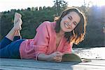 Smiling woman reading on deck