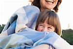 Mother and daughter wrapped in blanket