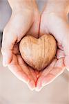 Hands holding carved wood heart